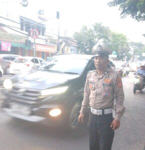 Petugas Satlantas Polres Cimahi berjaga di jalan utama untuk memastikan arus lalu lintas tetap lancar pada hari libur